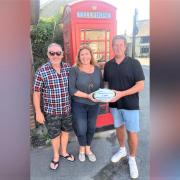 Roly Toombs, of Ventnor Rugby Club, right, presents a cheque for £250 to Indra Riches and Rob Engelgardt, leading the telephone box project in Niton.