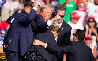 Donald Trump is helped off the stage by US Secret Service at a campaign event