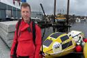 Russian consultant anaesthetist Leo Krivskiy standing in front of his row boat, Happy Socks.