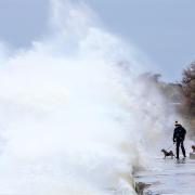 A dog walker comes face to face with a huge wave on Totland Bay promenade