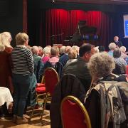 Derek, left, singing the song he wrote about his wife and dementia, with pianist Richard Britton conducting. The choir and volunteers are backing singers