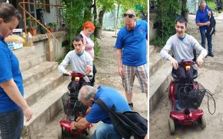 MAD-Aid volunteers showing Gabriel, a young man in the village of Ghelauza, how to use his new mobility scooter.